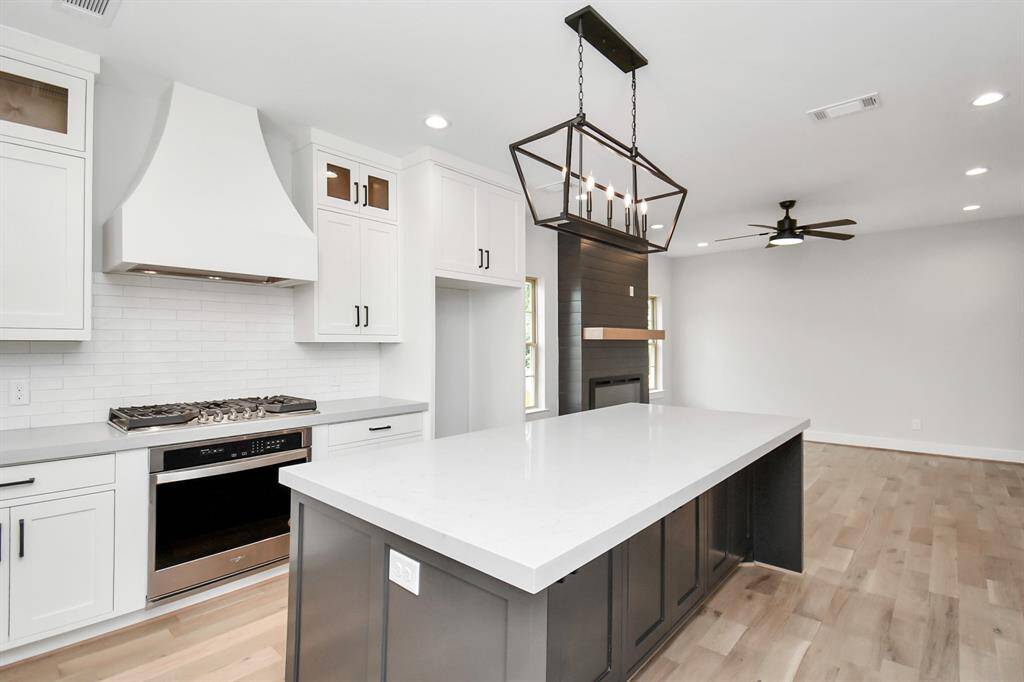 The oversized kitchen island accommodates seating for four, and we love the designer lighting fixture placed above it!