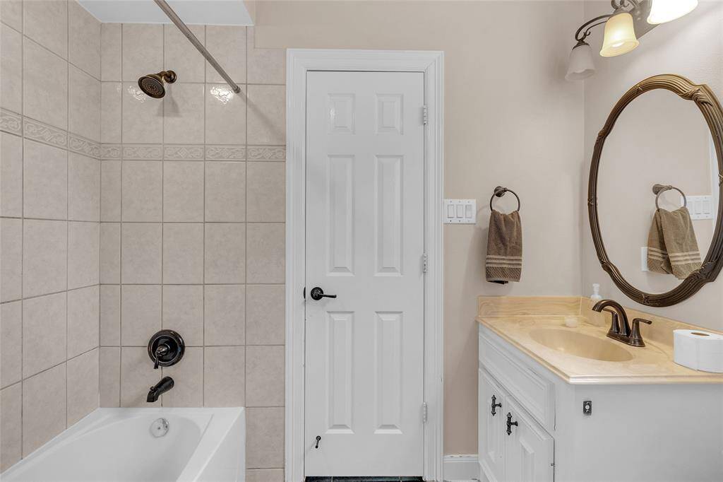 Ensuite bathroom with neutral tile work, featuring a combination shower and tub, a single vanity with ample counter space, and updated fixtures.