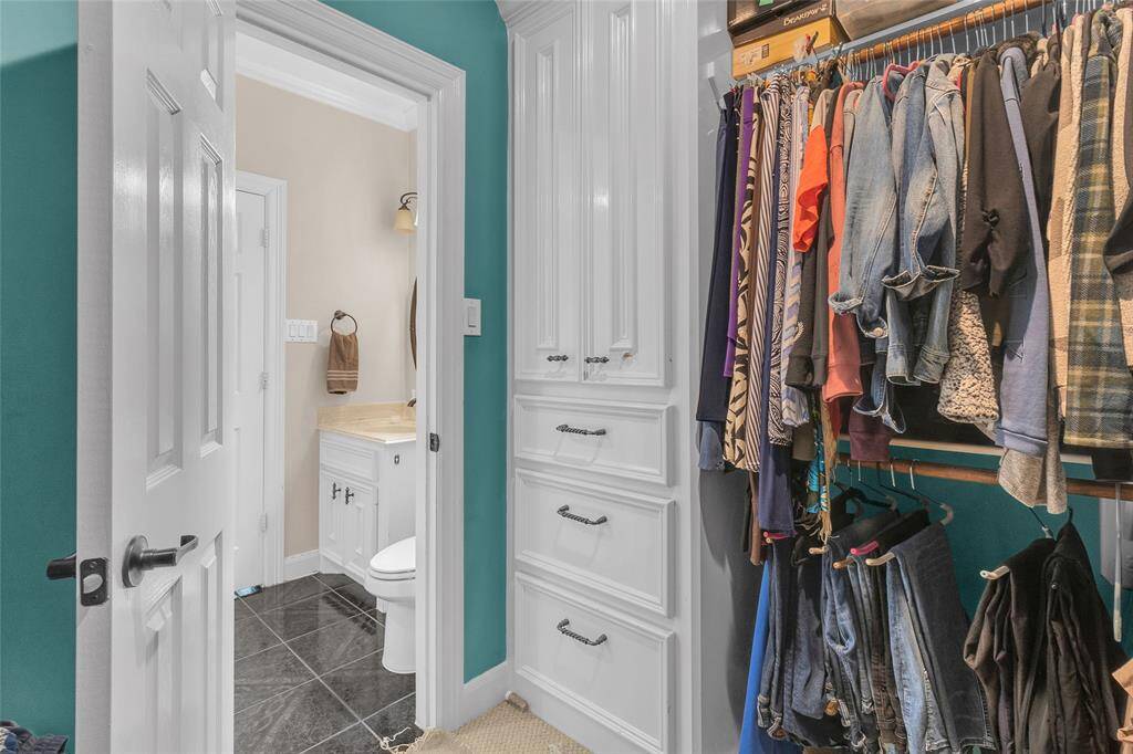 Walk-in closet featuring ample hanging space & storage shelves.