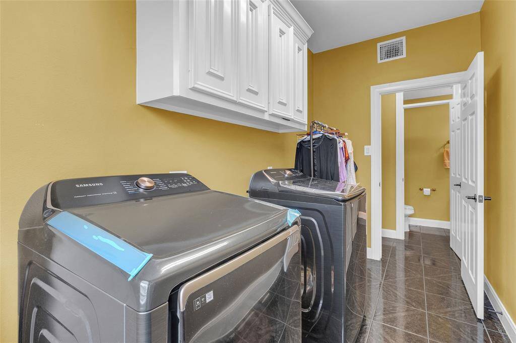 Streamlined laundry room boasting generous storage solutions and a bright, inviting atmosphere.