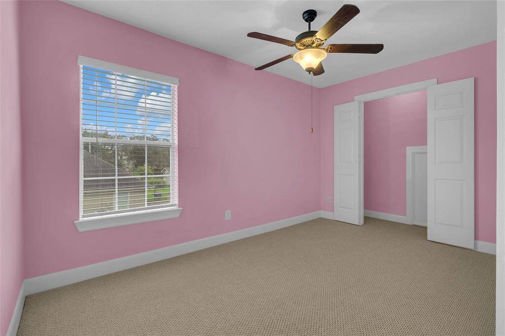 This ample and cozy retreat features plush carpeting, ample natural light, and a modern ceiling fan, creating a serene personal space.