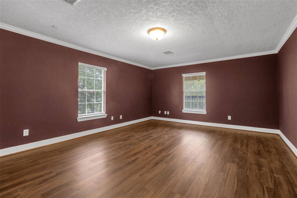 Discover the elegance of this inviting room, boasting lustrous hardwood flooring, an intricately textured ceiling, and ample natural light streaming through a generous window.