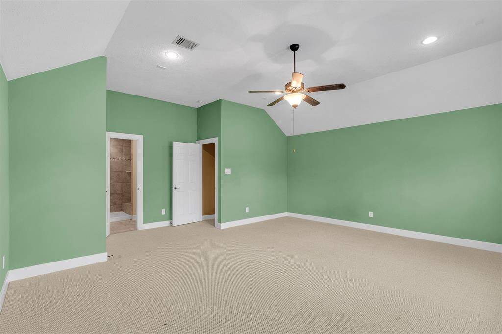 Spacious master suite with and ample natural light, featuring a modern ceiling fan and plush carpeting for ultimate comfort.