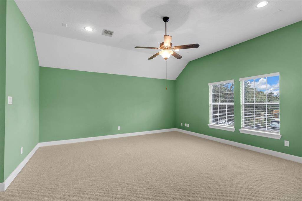Discover serene sophistication in this expansive master suite, bathed in natural light, cozy carpet, and a sleek ceiling fan for your comfort.
