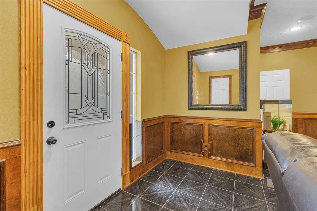Welcome in style with this sophisticated foyer featuring a stunning stained-glass door and sophisticated wood trim, perfectly complemented by sleek tile flooring.