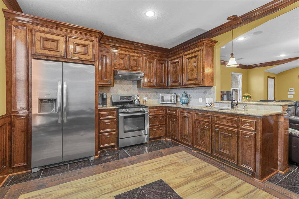 Gourmet kitchen featuring stainless steel appliances, rich wooden cabinetry, and sleek granite countertops, perfect for culinary enthusiasts.