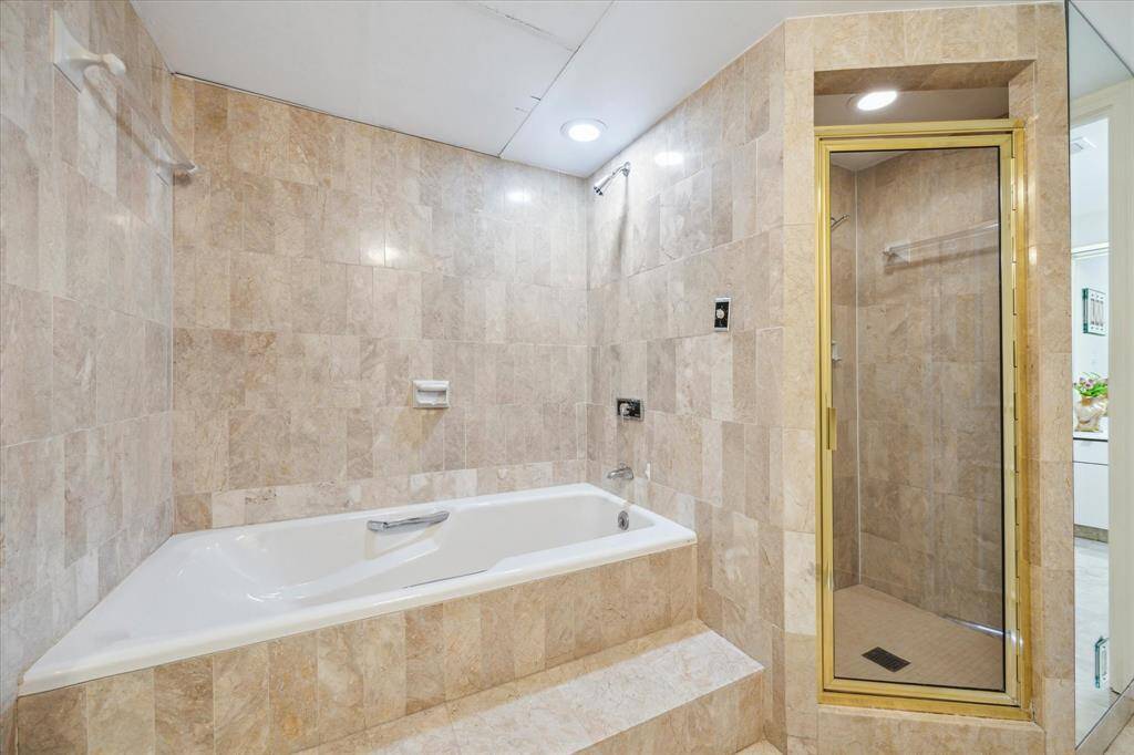 Luxurious primary bathroom featuring a spacious tub and sleek shower.