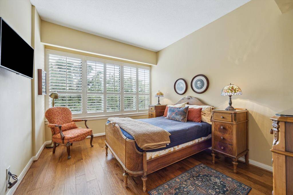Cozy 10x11 guest bedroom featuring elegant wood shutters and beautiful wood floors.