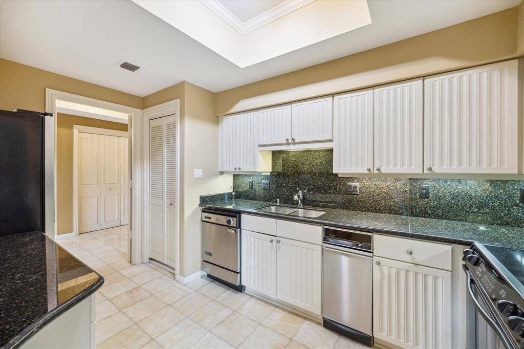 Discover a contemporary galley kitchen with sleek white cabinets, stainless steel appliances, and stunning granite countertops.