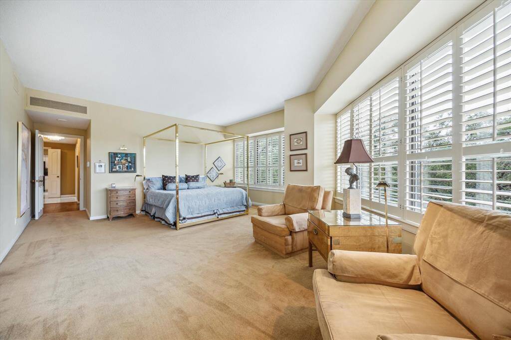 Spacious bedroom with elegant design, abundant natural light, and a cozy seating area.