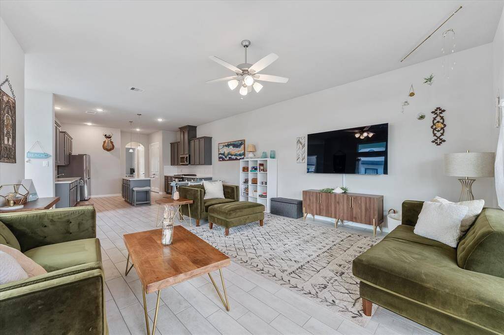 Step into this inviting living room, where sleek tile flooring seamlessly flows into the open-concept kitchen and dining area.