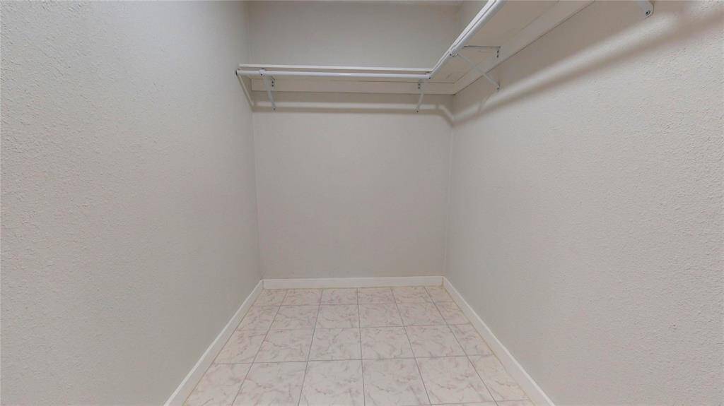 This is a compact, empty walk-in closet with built-in shelving and hanging rods.