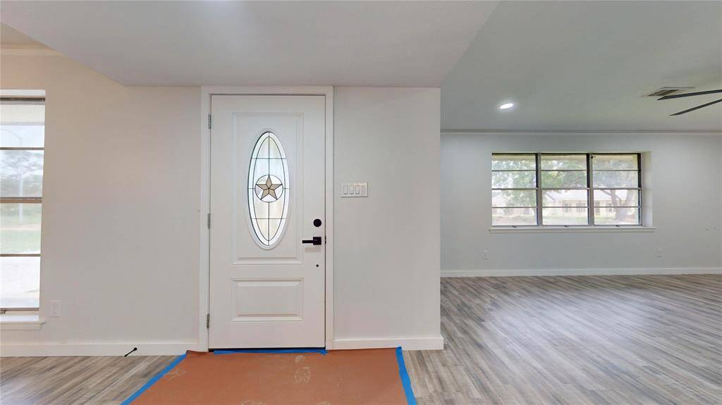 This is a spacious, well-lit room, fresh neutral walls, and a decorative front door with a glass inset.