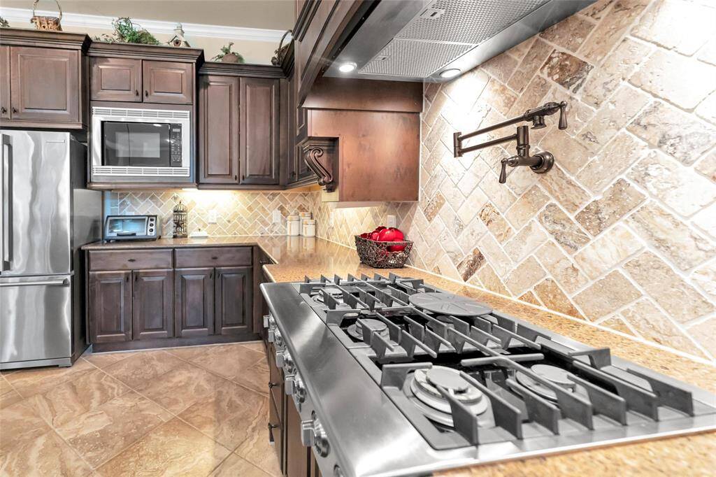Six burner gas cooktop with a pot filler above.