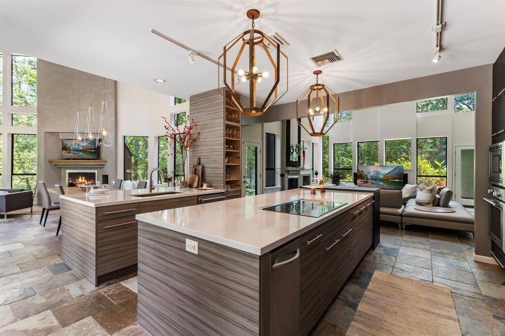 Two well planned islands are topped with crisp, clean Solid Surface and feature designer storage solutions and seating beneath designer lighting.