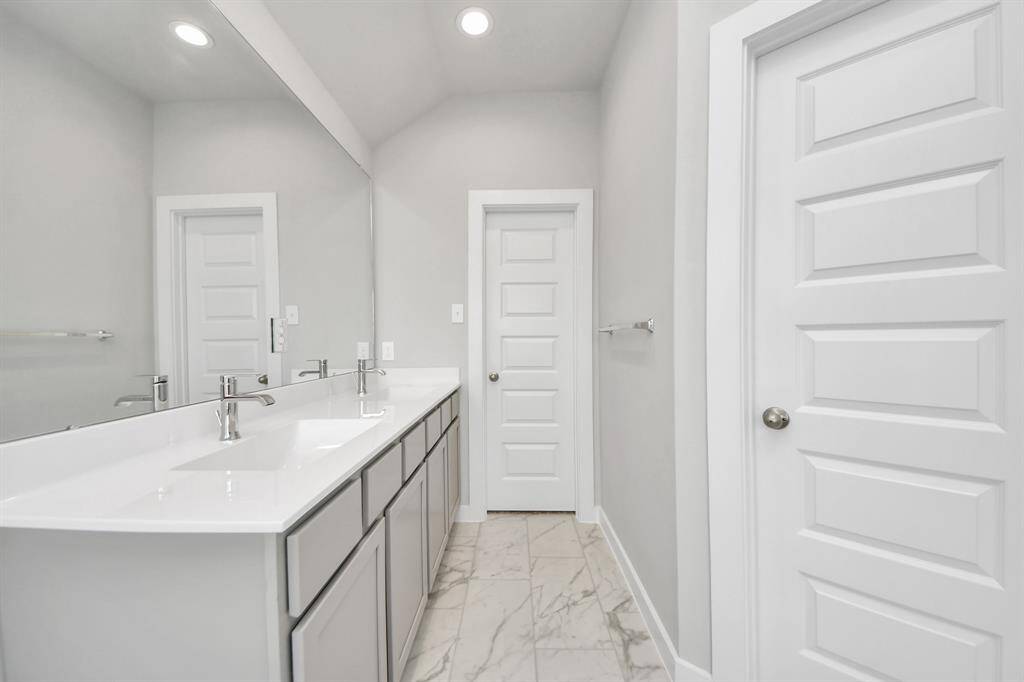 Elevate your daily routine at the elegant vanity, now equipped with double sinks, light countertops, modern hardware, and beautiful recessed lights.