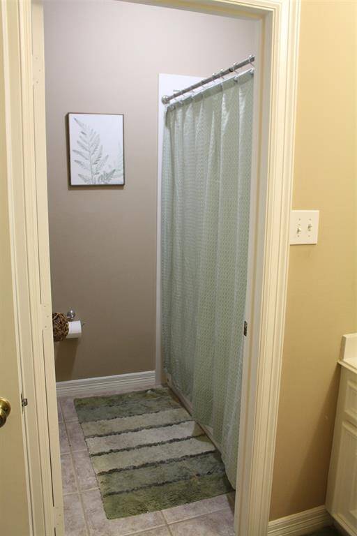 Shower/Tub Combo with toilet separated from vanity area in guest bath.