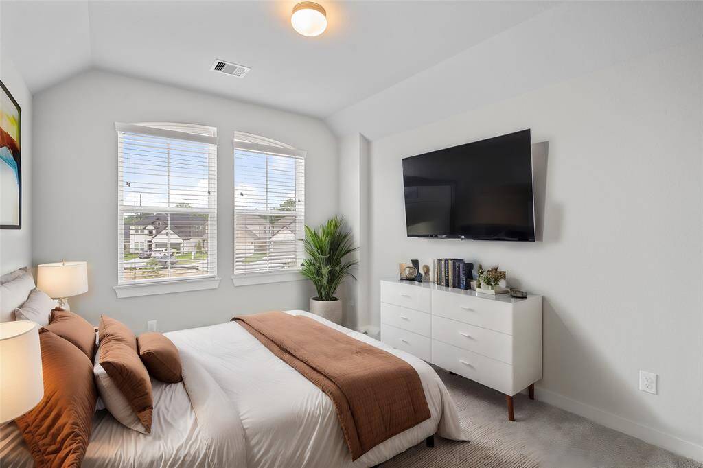 Secondary bedroom features plush carpet, custom paint, high ceilings, and large window with privacy blinds.