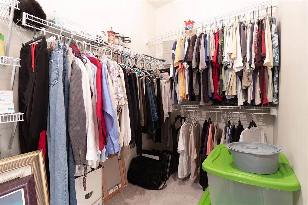 Primary walk-in closet featuring ample hanging space across multiple racks, with additional room the floor and overhead shelves.