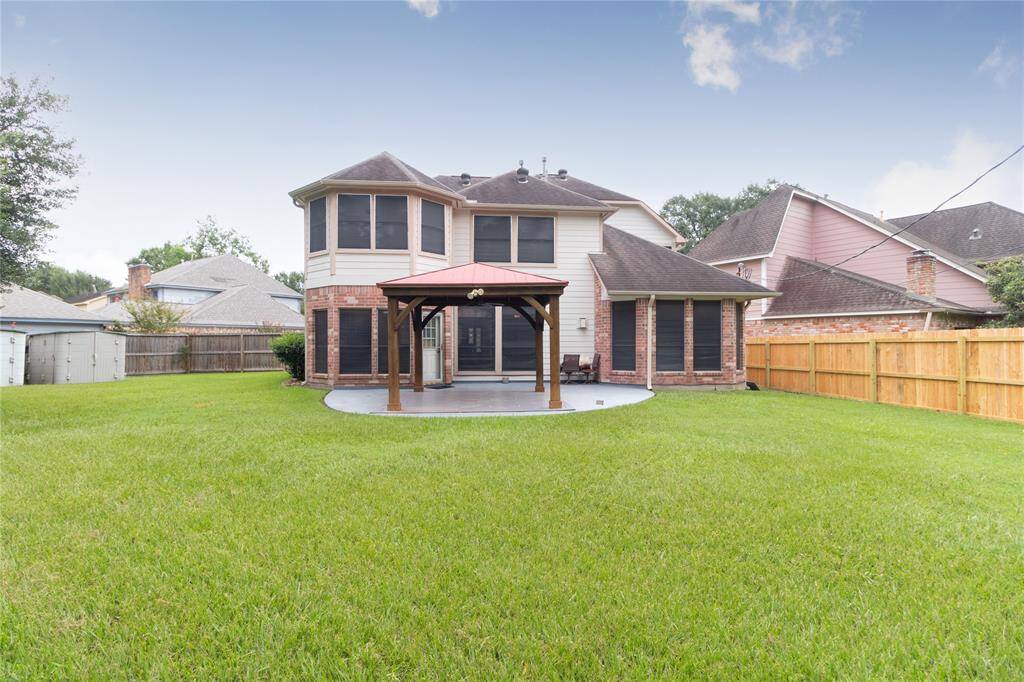 Large backyard with a well-maintained lawn and a covered patio area, ideal for outdoor living and entertainment. The property is fenced for privacy.