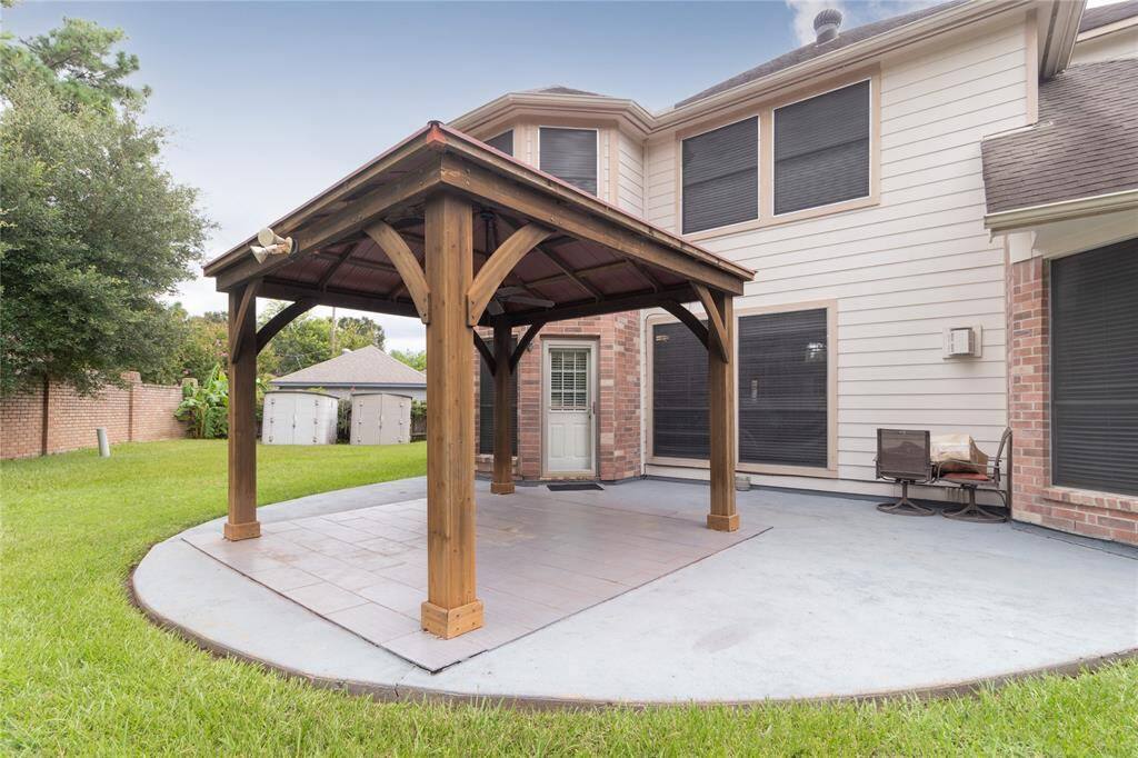 Outdoor covered patio area with a ceiling fan, overlooking a fenced backyard.