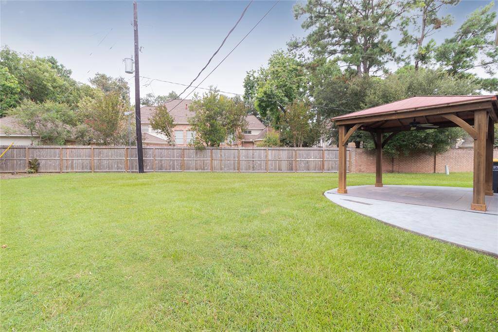 Spacious backyard with a well-maintained lawn, a wooden gazebo for outdoor activities, and a privacy fence encompassing the area.