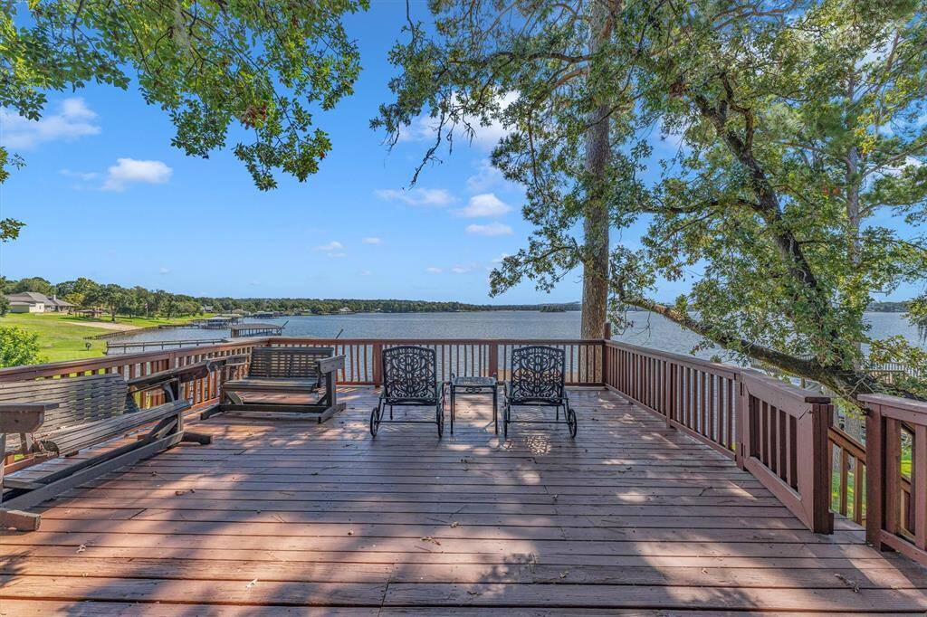 Lakeside deck with a serene water view, surrounded by trees, offering a perfect spot for relaxation and entertainment.