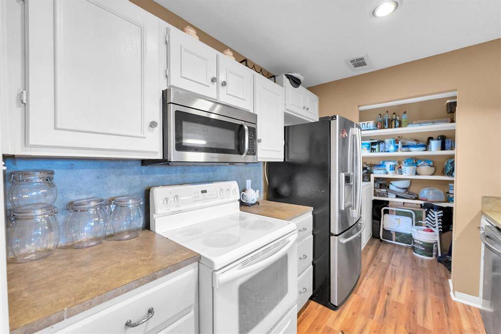 This kitchen features white cabinetry, laminate countertops and a walk-in open pantry for storage.