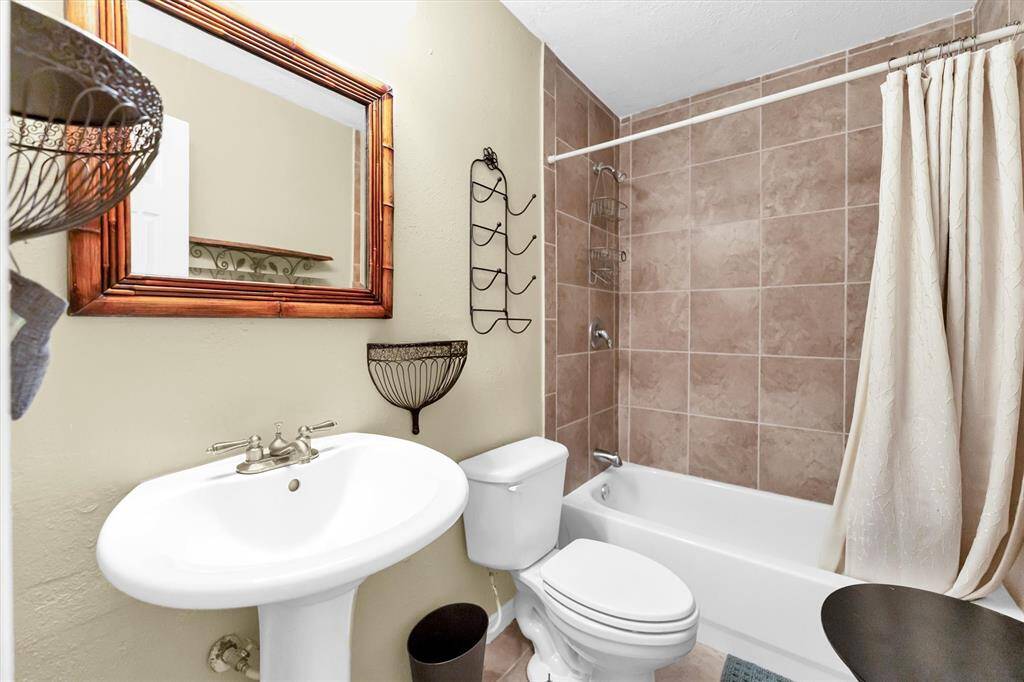 This bathroom features a pedestal sink and a bathtub with shower.