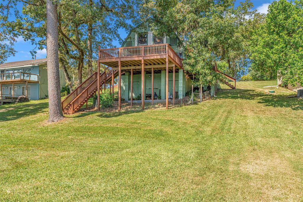 A beautiful two-story lake house with large windows, a spacious deck overlooking the water, and surrounded by lush greenery. Creates a peaceful and picturesque setting perfect for relaxation.