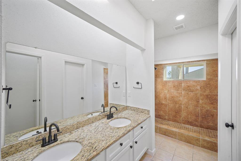 This incredible Primary Bathroom is complete with tile floors, double sinks, granite countertops and backsplash, and bright lighting.