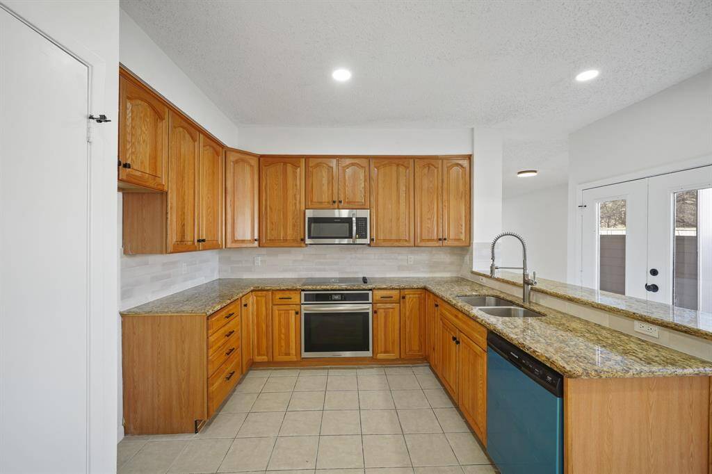 This kitchen area is complete with recessed lighting, gorgeous tile floors, granite countertops and stainless steel appliances.