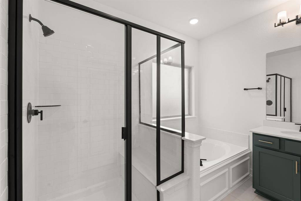 This additional view of your primary bathroom features tile flooring, fresh paint, walk-in shower, a separate garden tub, and a large walk-in closet.
