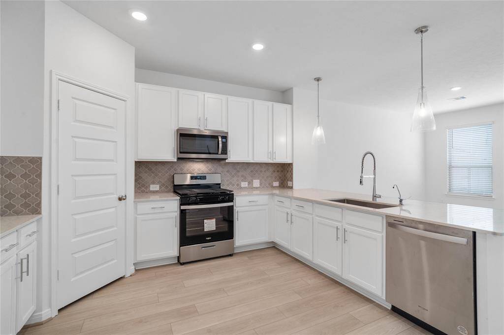 This spacious kitchen features high ceilings, stained wood cabinets, granite countertops, SS appliances, modern tile backsplash, recessed and pendant lighting, space for breakfast bar, and a pantry all overlooking your huge family room.