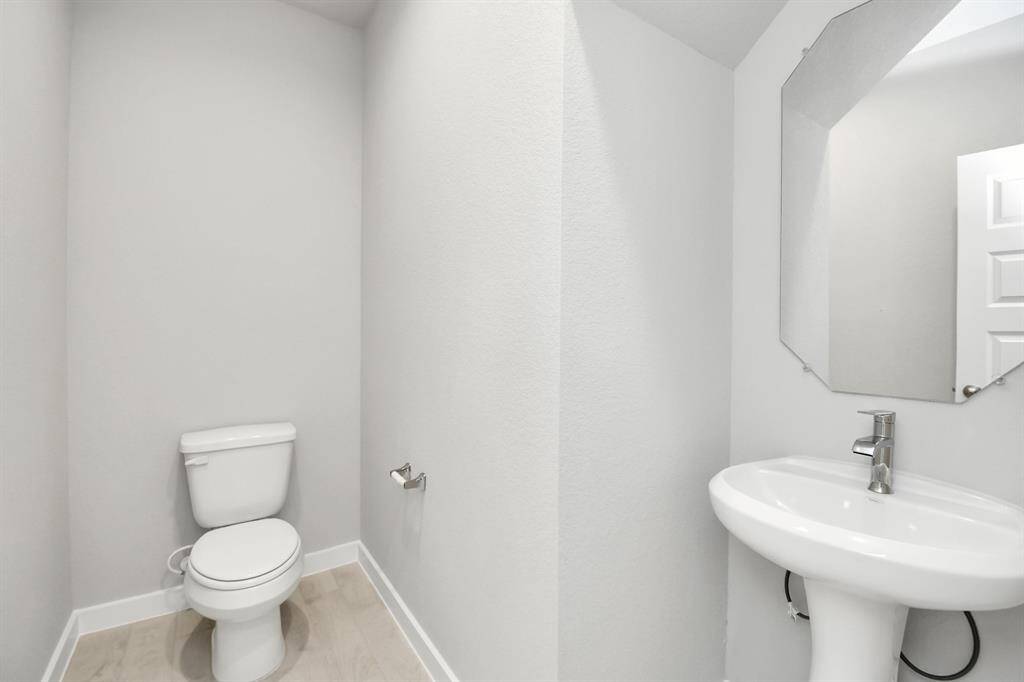 This half bathroom features a stylish pedestal sink, modern hardware, and bright recessedlighting, creating a sleek and inviting space.