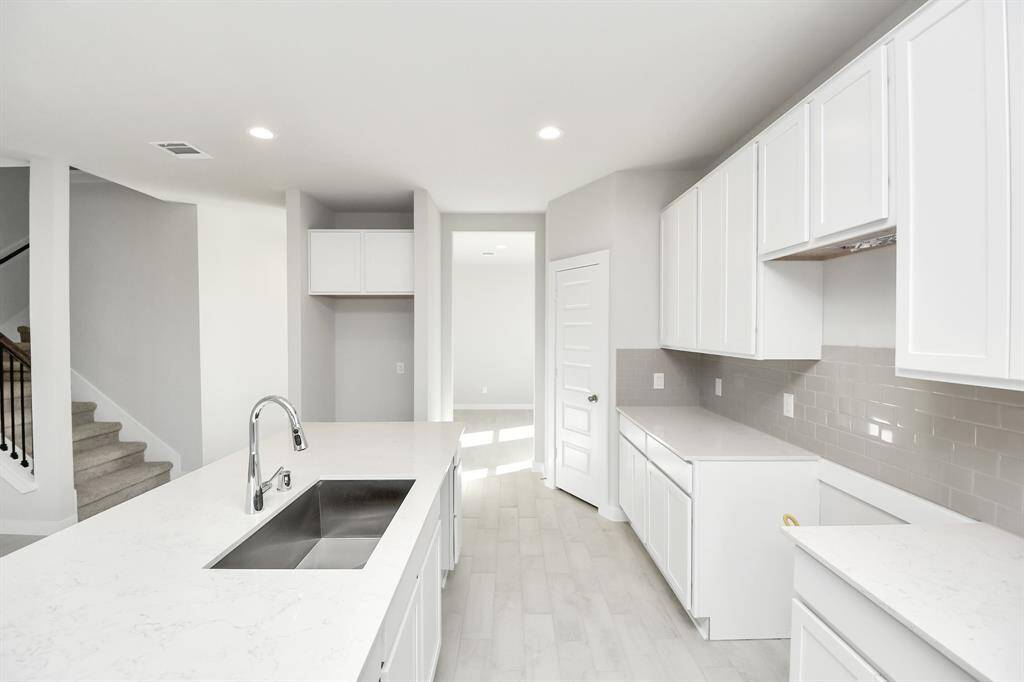 This kitchen is by far any chef’s dream! This spacious kitchen features high ceilings, lightstained wood cabinets, granite countertop, SS appliances, modern tile backsplash,recessed lighting, extended counter space, granite kitchen island with double sink, andspace for breakfast bar, and a walk-in pantry all overlooking your huge family room.