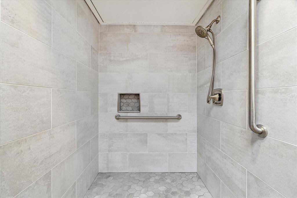 The generously sized shower has porcelain tile, and brushed nickel hardware.