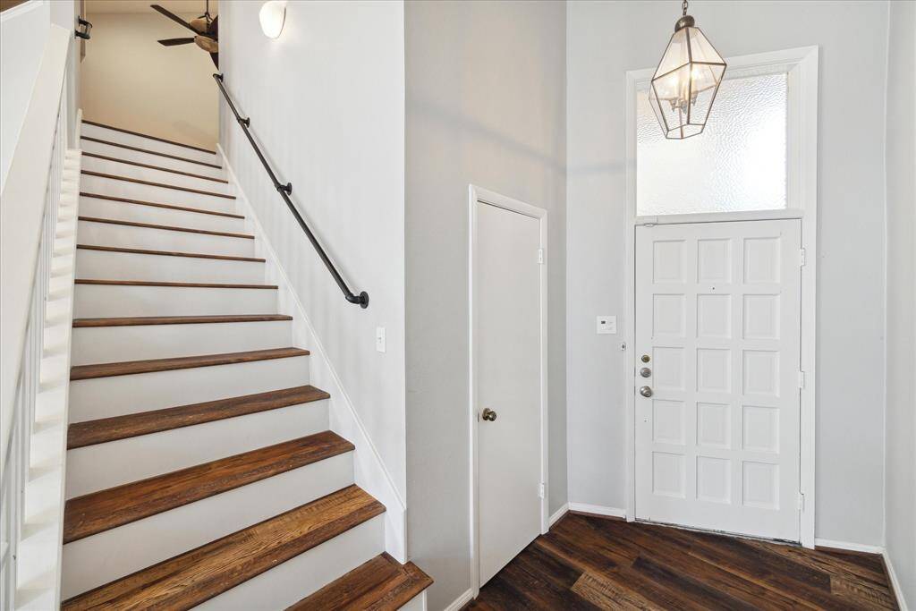 This handsome brick fireplace anchors the space and is flanked by two floors to ceiling windows along with transoms allowing for an abundance of natural light to flow into the home. (Virtually Staged)