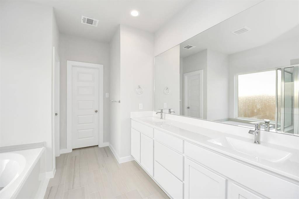 Elevate your dailyroutine at the elegant vanity, now equipped with double sinks, lightcountertops, modern hardware, and beautiful recessed lights.