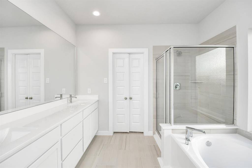 Escape to a spa-like oasis in this primary bathroom. Enjoy a walk-in showerwith tile surround, a separate garden tub with custom detailing, and an elegantvanity featuring light countertops, modern hardware, and beautiful recessed lights.Experience luxury and relaxation in every detail.