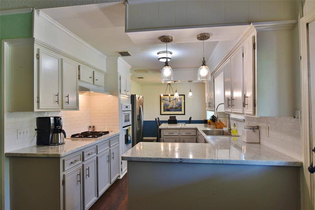 Kitchen area with marble counters, subway back-splash, updated lighting, and a style all its own!  Crown molding adds a nice architectural touch....