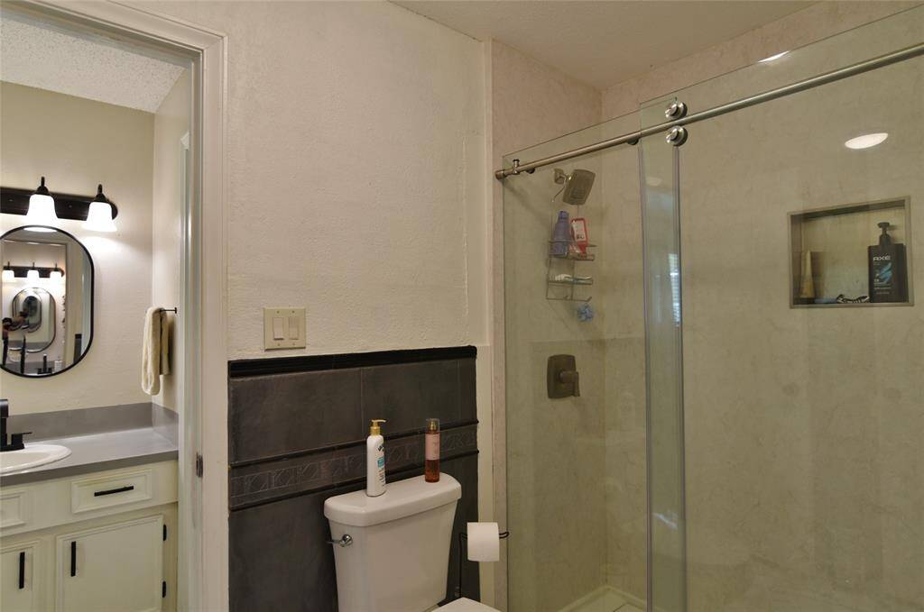 Primary bath/toilet area sits between the two vanity areas ..... shower has updated glass sliding shower doors, large shower head, and inset for shampoo/soaps....