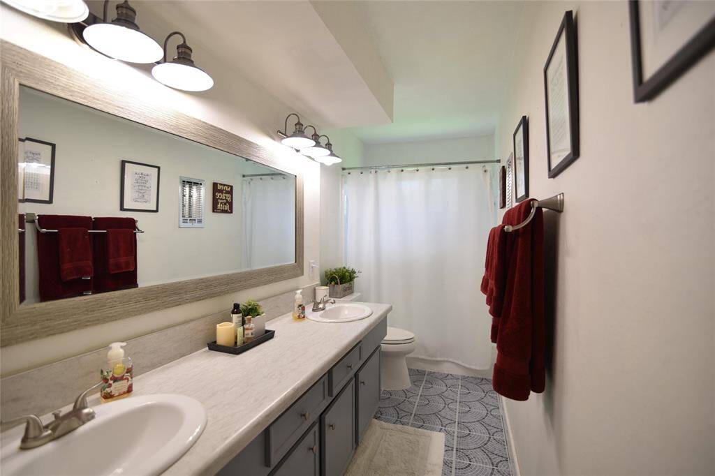 Hallway bath has double sinks, updated lighting fixtures and a full storage/linen closet....tub/shower combo with window for good natural light in the space....