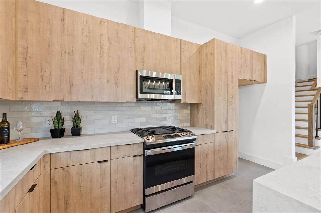 Arcadia Yellow Walnut cabinetry with Artic White with Coral Luster Quartz Countertops.