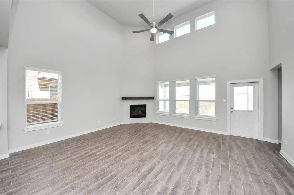 Welcome family and guests to your charming living room! With its high ceilings, recessed lighting, ceiling fan, custom paint, beautiful flooring, and large windows that let in abundant natural light, this room is perfect for gatherings.