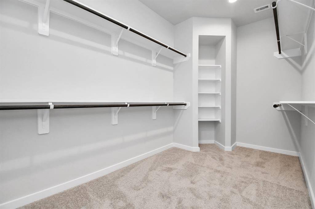 Walk-in closet that epitomizes luxury and practicality. This generously sized space features built-in shelving, offering abundant room for impeccable organization. High ceilings and recessed lighting create a bright and welcoming ambiance.