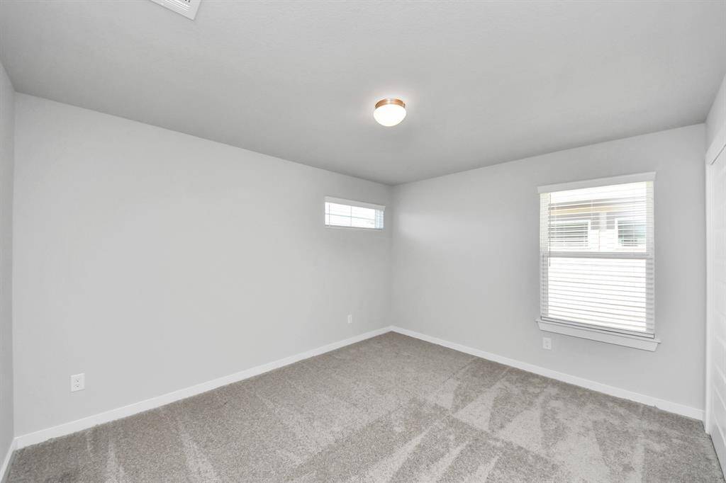 Secondary bedroom features plush carpeting, large windows that let in plenty of natural light, bright paint, and spacious closets.