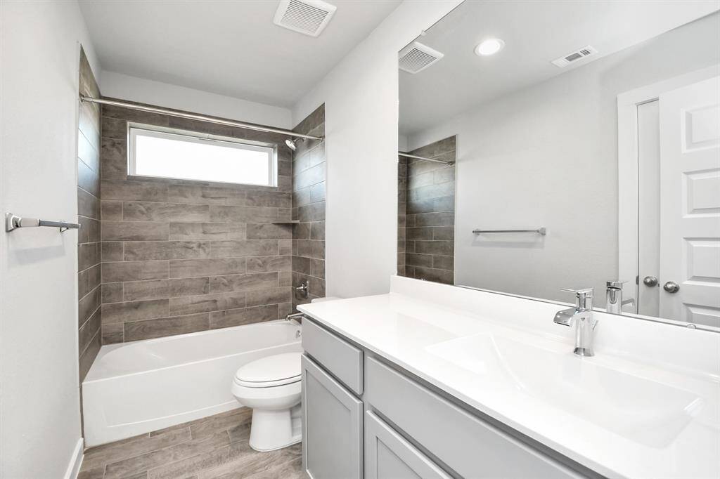 Secondary bath features tile flooring, bath/shower combo with tile surround, light stainedwood cabinets, beautiful light countertop.