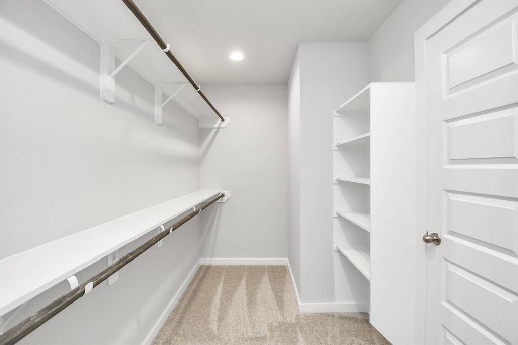 Walk-in closet that epitomizes luxury and practicality. This generously sizedspace features built-in shelving, offering abundant room for impeccableorganization. High ceilings and recessed lighting create a bright and welcoming ambiance.