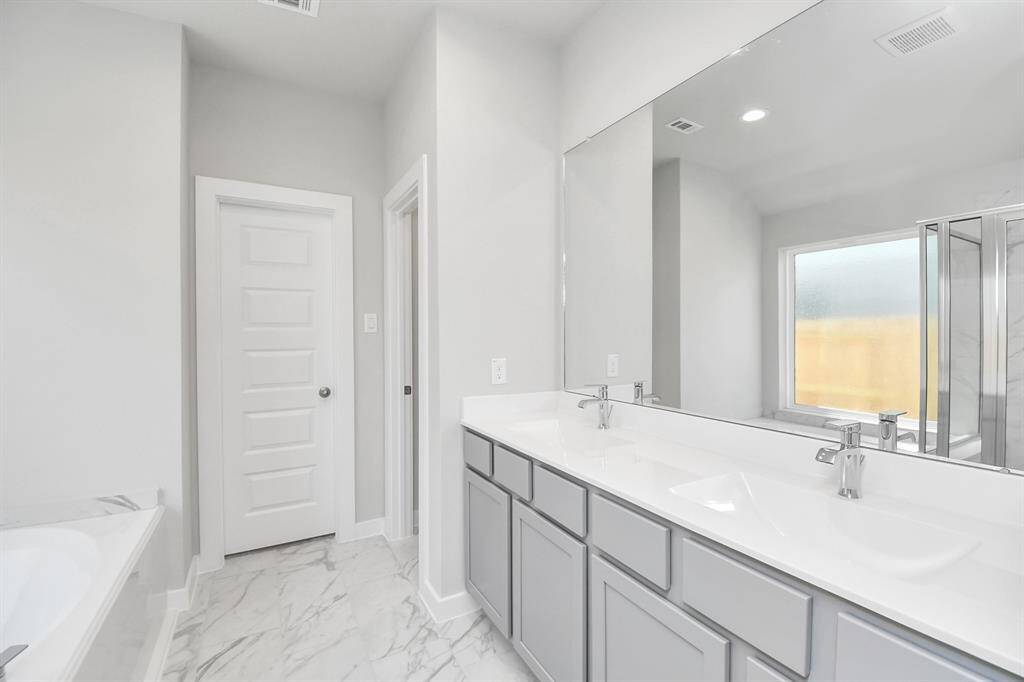 Elevate your dailyroutine at the elegant vanity, now equipped with double sinks, lightcountertops, modern hardware, and beautiful recessed lights.